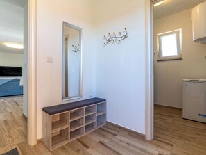 A hallway with a wooden bench, a mirror, a wall-mounted light fixture, and a window. - Villa Mare by Interhome (Rab/Lopar)