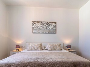 A bedroom with a bed, two bedside lamps, a wall-mounted artwork, and a nightstand. - Villa Mare by Interhome (Rab/Lopar)