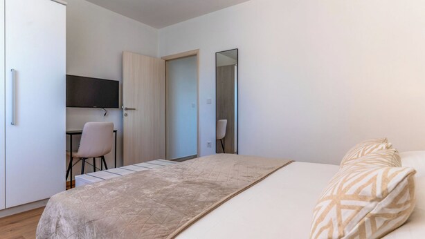 Ein Schlafzimmer mit einem Bett, einem Schreibtisch, einem Stuhl und einem Kleiderschrank.