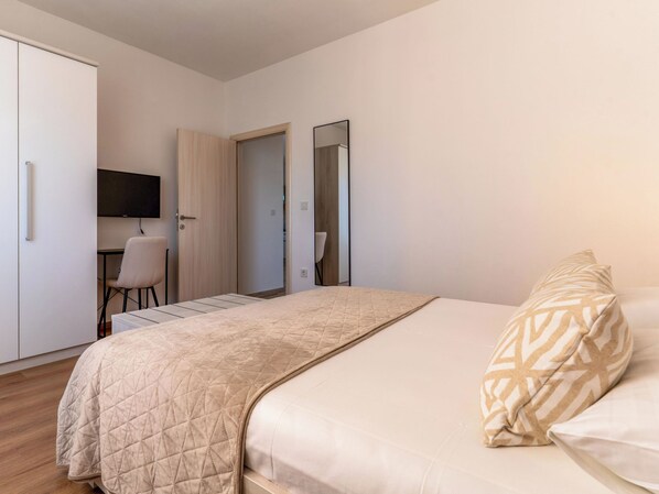 Een slaapkamer met een bed, een bureau, een stoel, een kast en een spiegel.