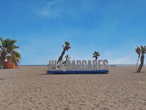 A beach with a sign reading '#LEBARGUES' and palm trees. - Les Supers Marines by Interhome (Le Barcarès)