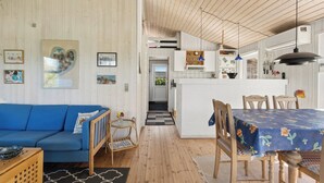 A cozy interior with a blue sofa, wooden dining table, and a kitchen area. - Charming holiday home near the beach (Hejls)