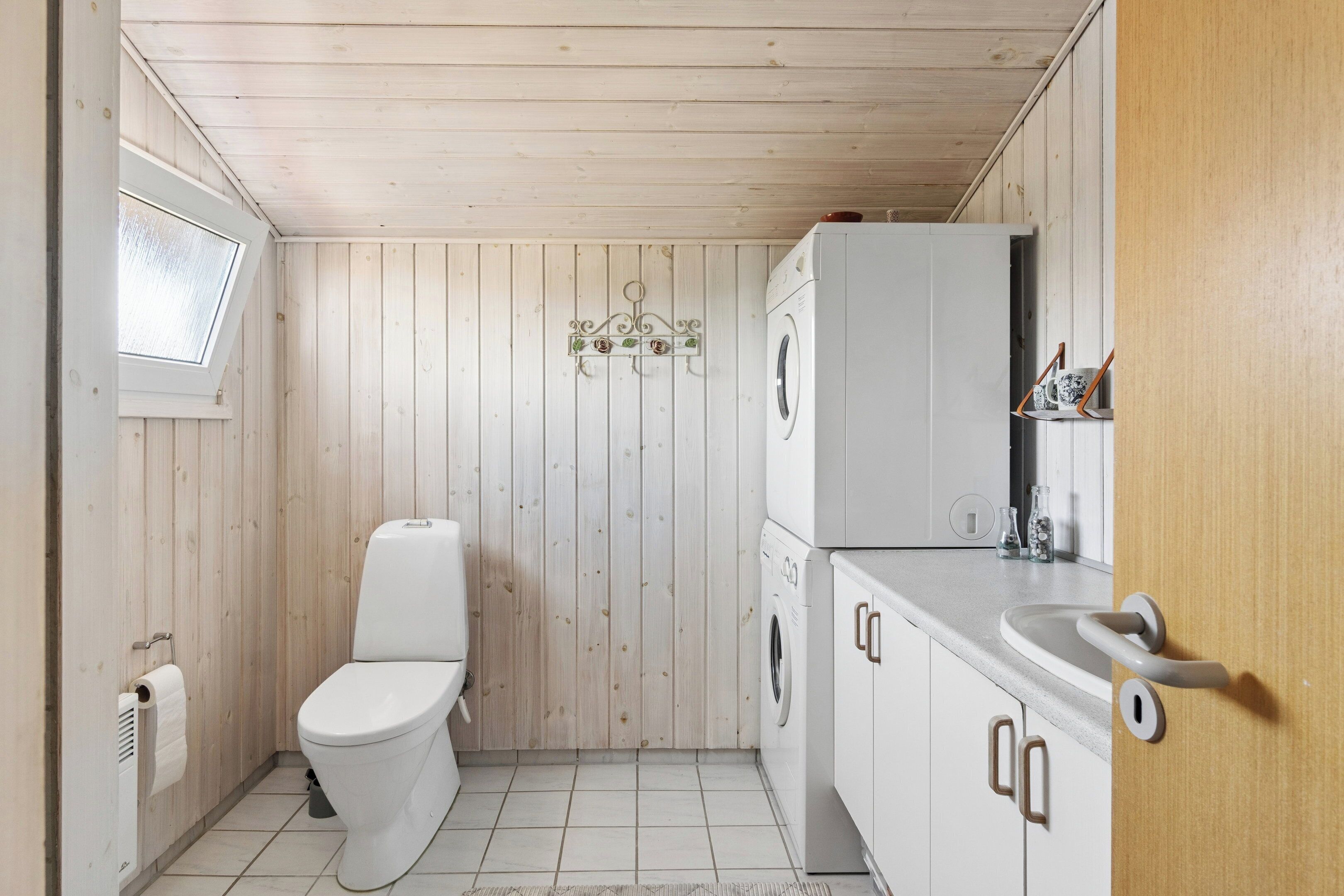 A compact bathroom with a toilet, washing machine, and sink.