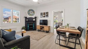 Un salon moderne doté d’une cheminée, d’un téléviseur, d’une table à manger et de sièges confortables.