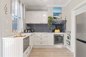 A modern kitchen with white cabinetry, a tiled backsplash, and a built-in oven.