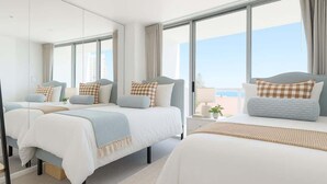 Ein Hotelzimmer mit drei Betten, großen Fenstern, einem Balkon und Blick auf die Stadt.