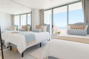 A hotel room with three beds, large windows, a balcony, and a view of the city. - Modern 2-Bedroom Oasis with Pool (Surfers Paradise)