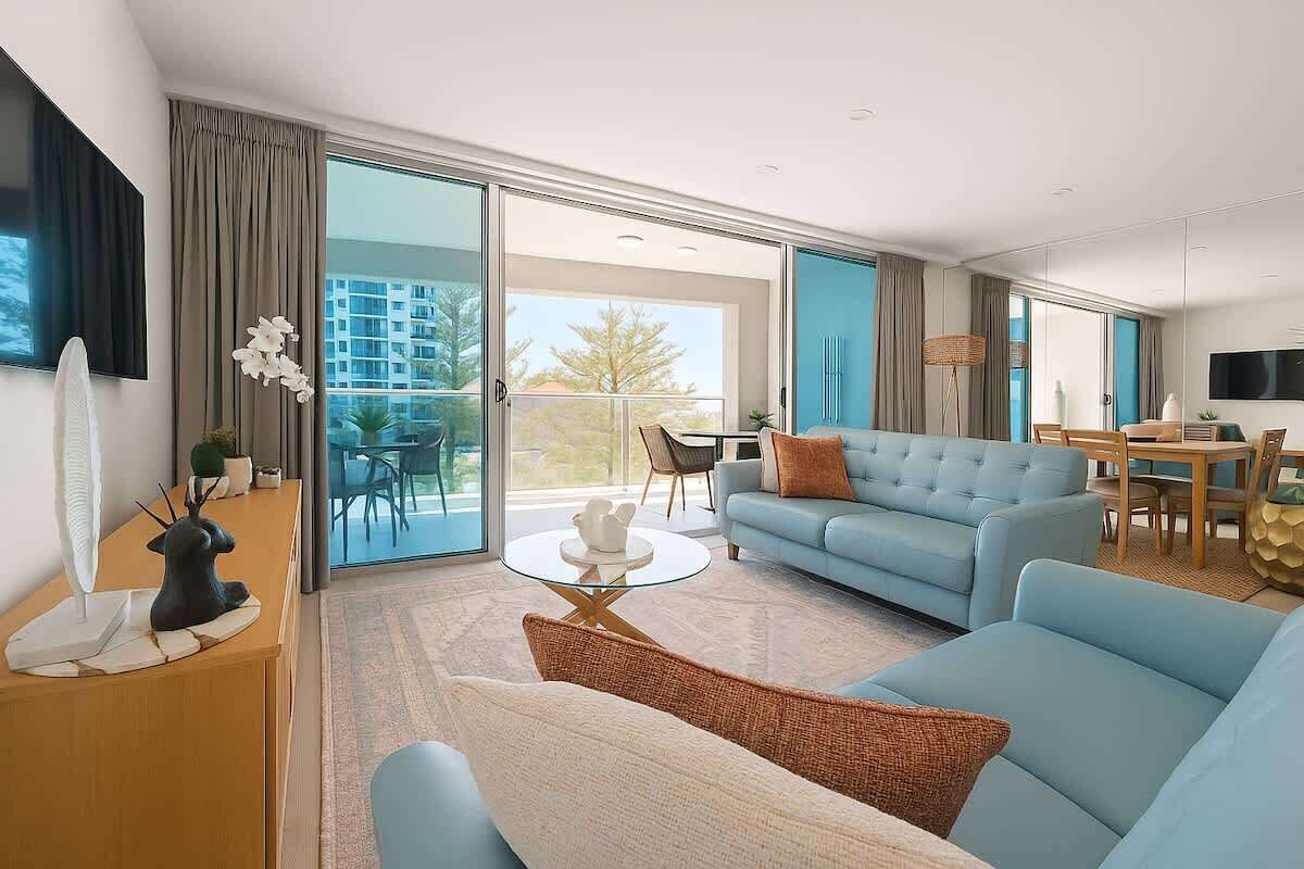 Een moderne hotelkamer met balkon, een bank, een eettafel en een televisie.