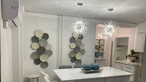 Een moderne keuken met een centraal eiland, hanglampen en decoratieve wandkunst.