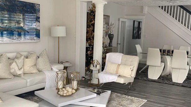 Een moderne woonkamer met een witte bank, een blauwe poef en een salontafel met decoratieve objecten.