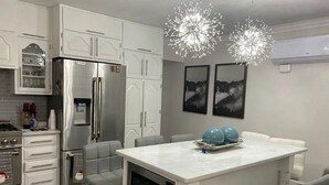 Een moderne keuken met een centraal kookeiland, roestvrijstalen apparatuur en een eethoek met een witte tafel en stoelen.