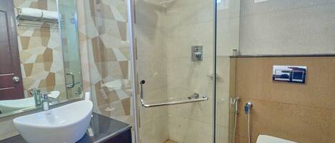 A bathroom with a glass-enclosed shower, a white sink, and a toilet.