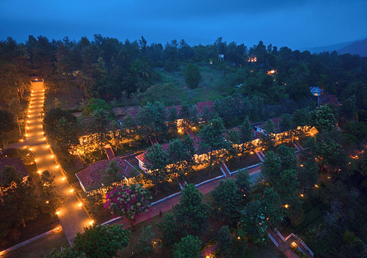 An aerial view of a well-lit, tree-lined area with pathways and buildings, suggesting a resort or hotel setting.