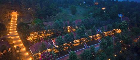 An aerial view of a well-lit, tree-lined area with pathways and buildings, suggesting a resort or hotel setting.