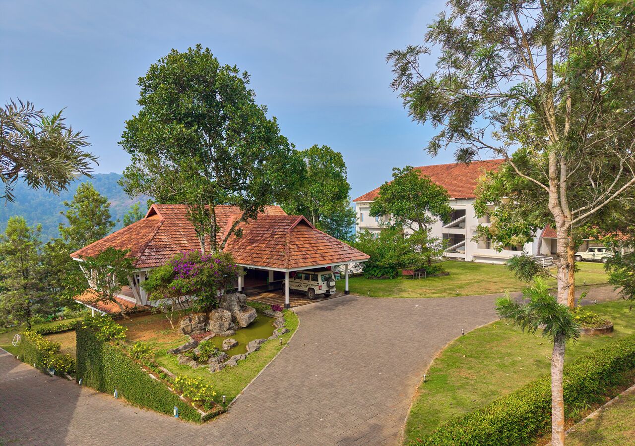 A hotel with a red-roofed structure, a covered parking area, and a landscaped garden.