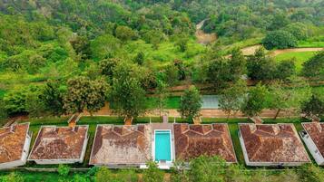 Filas de cabañas con una piscina central, rodeadas por un bosque denso.