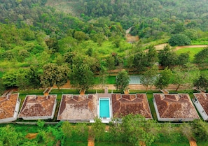 Filas de cabañas con una piscina central, rodeadas por un bosque denso.