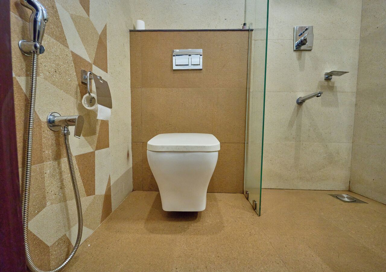 A small bathroom with a toilet, a shower, and a glass partition.
