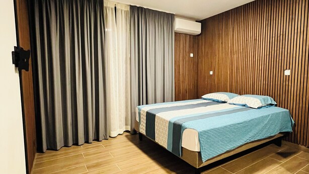 Un dormitorio con cama, cortinas, paneles de madera y suelo de baldosas.