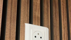 Un enchufe eléctrico blanco sobre una superficie de madera.