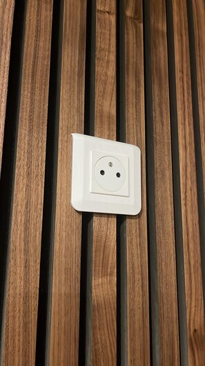 Un enchufe eléctrico blanco sobre una superficie de madera.