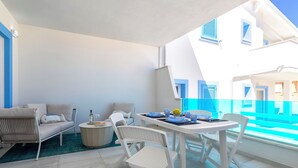 Ein Balkon mit Esstisch, Stühlen und einer Couch.