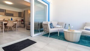 Eine moderne Wohnung mit Küche, Essbereich, Sofa, Couchtisch und einer Schiebeglastür, die auf einen Balkon führt.