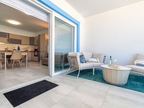 Eine moderne Wohnung mit Küche, Essbereich, Sofa, Couchtisch und einer Schiebeglastür, die auf einen Balkon führt.