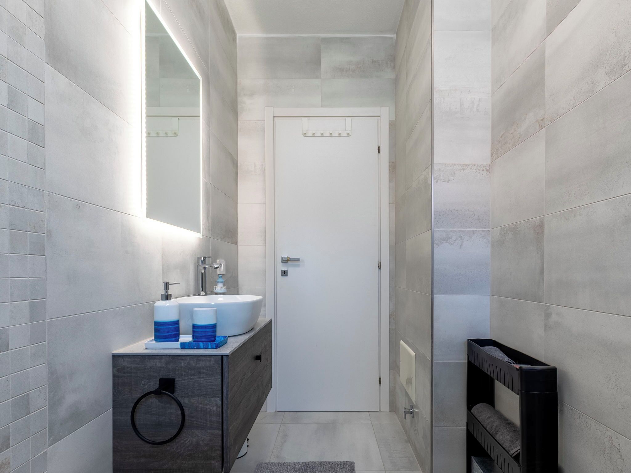 Een moderne badkamer met een wit wastafelmeubel, spiegel en donker houten onderkast.