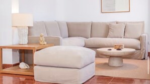 Un salon moderne avec un canapé beige, une petite table et une lampe.