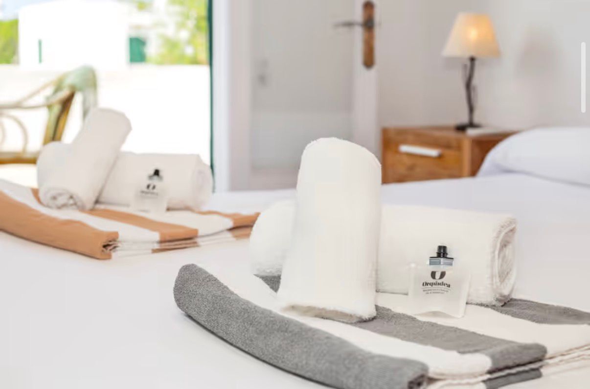 Cama bem arrumada com toalhas dobradas e um frasco de loção.