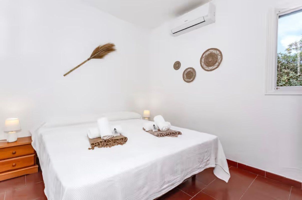 Ein Hotelzimmer mit einem Bett, Nachttischlampen, einer Wand-Klimaanlage und Wanddekoration.