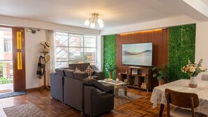 Ein modernes Wohnzimmer mit Sofa, Fernseher und Essbereich.