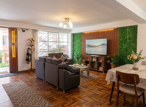 Ein modernes Wohnzimmer mit Sofa, Fernseher und Essbereich.