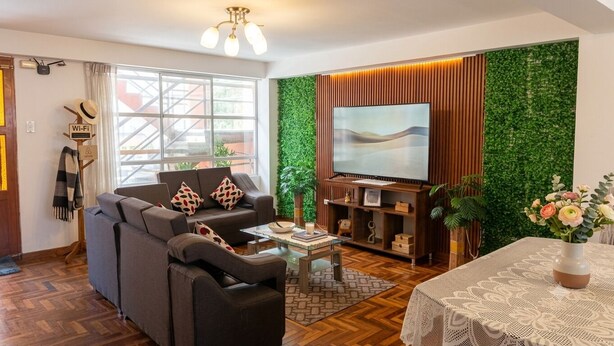 Ein modernes Wohnzimmer mit einer Couch, einem Couchtisch und einem Flachbildfernseher an einer grünen Wand.