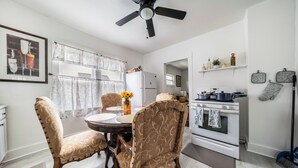 A dining area with a round table, two chairs, a ceiling fan, a refrigerator, an oven, and a window with curtains. - 10 min to University Circle - Central Location (Cleveland)