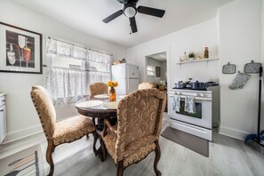 A dining area with a round table, two chairs, a ceiling fan, a refrigerator, an oven, and a window with curtains. - 10 min to University Circle - Central Location (Cleveland)