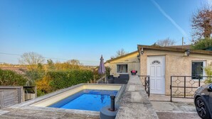 A swimming pool, a wooden deck, a house with a door, and a car parked on a paved area. - Chalet-type house for 7 people with swimming pool near Disneyland Paris (EuroDisney) (Villiers-sur-Morin)