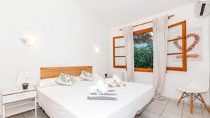 Ein Schlafzimmer mit Bett, Nachttisch, Stuhl und einem Fenster mit Vorhängen.