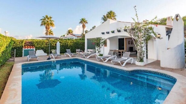 Ein moderner Poolbereich mit Liegestühlen, einem Pool und einem Gebäude mit markanter Architektur.