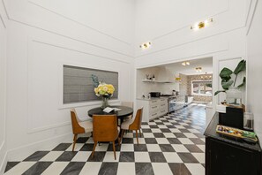 A modern kitchen with white cabinetry, a black and white checkered floor, and a dining area with a round table and chairs. - Luxury Main-Level 2BR Private Home close to UBC (Vancouver)