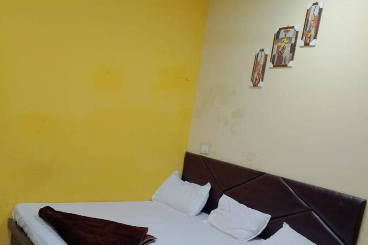A bed with white linens, a brown headboard, and a brown throw blanket.