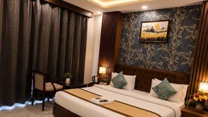 Une chambre d’hôtel moderne avec un grand lit, un ventilateur de plafond et une table de chevet avec une lampe.