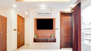 Une chambre d’hôtel équipée d’un lit, d’un téléviseur fixé au mur, d’un appareil de climatisation et de portes en bois.