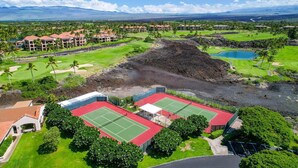 Un campo de golf con varios edificios, una cancha de tenis y una gran extensión de agua.