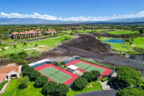 Ein Golfplatz mit mehreren Gebäuden, einem Tennisplatz und einem großen Wasserspiegel.