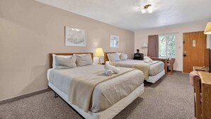 Une chambre avec deux lits, un bureau, une chaise, une lampe et un téléviseur.