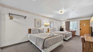 A hotel room with two beds, a desk, a chair, a television, and a window. - Eagle Motel Suite 112 (Manitou Springs)