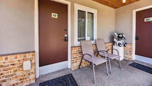 A covered porch with two doors, a window, and a bear statue.