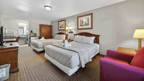 A hotel room with two beds, a desk, a chair, a TV, and a bathroom. - Eagle Motel Suite 118 (Manitou Springs)